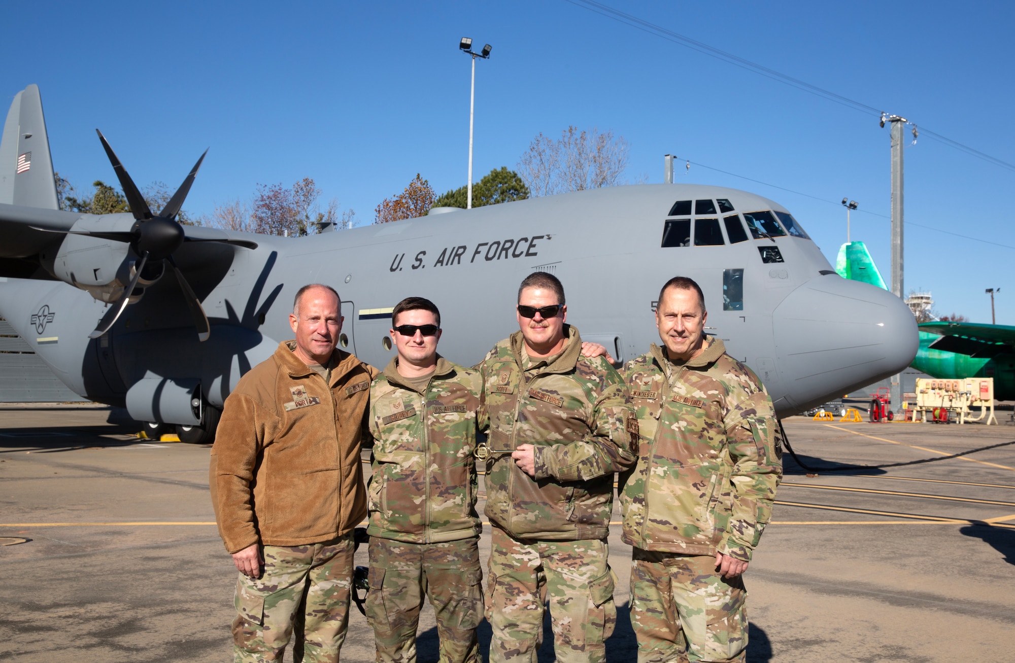 Members of the 910th Maintenance Group pose for a photo while holding a ceremonial aircraft key in front of the unit’s newest C-130J-30 Super Hercules aircraft at the Lockheed Martin assembly plant in Marietta, Georgia, Dec. 6, 2024.