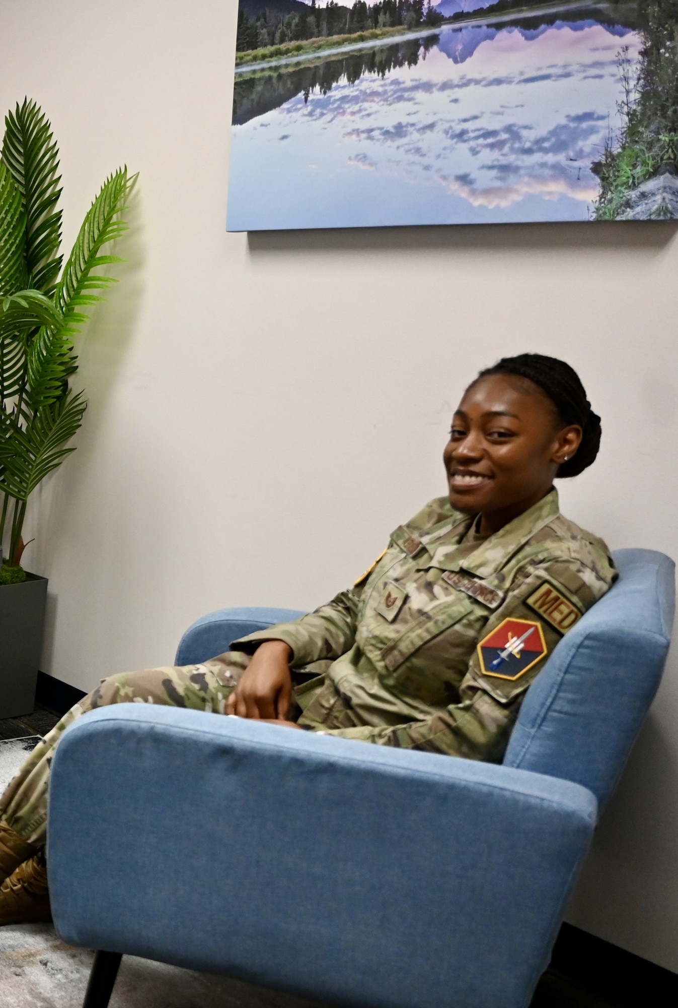 A woman in uniform sits in a blue chair.