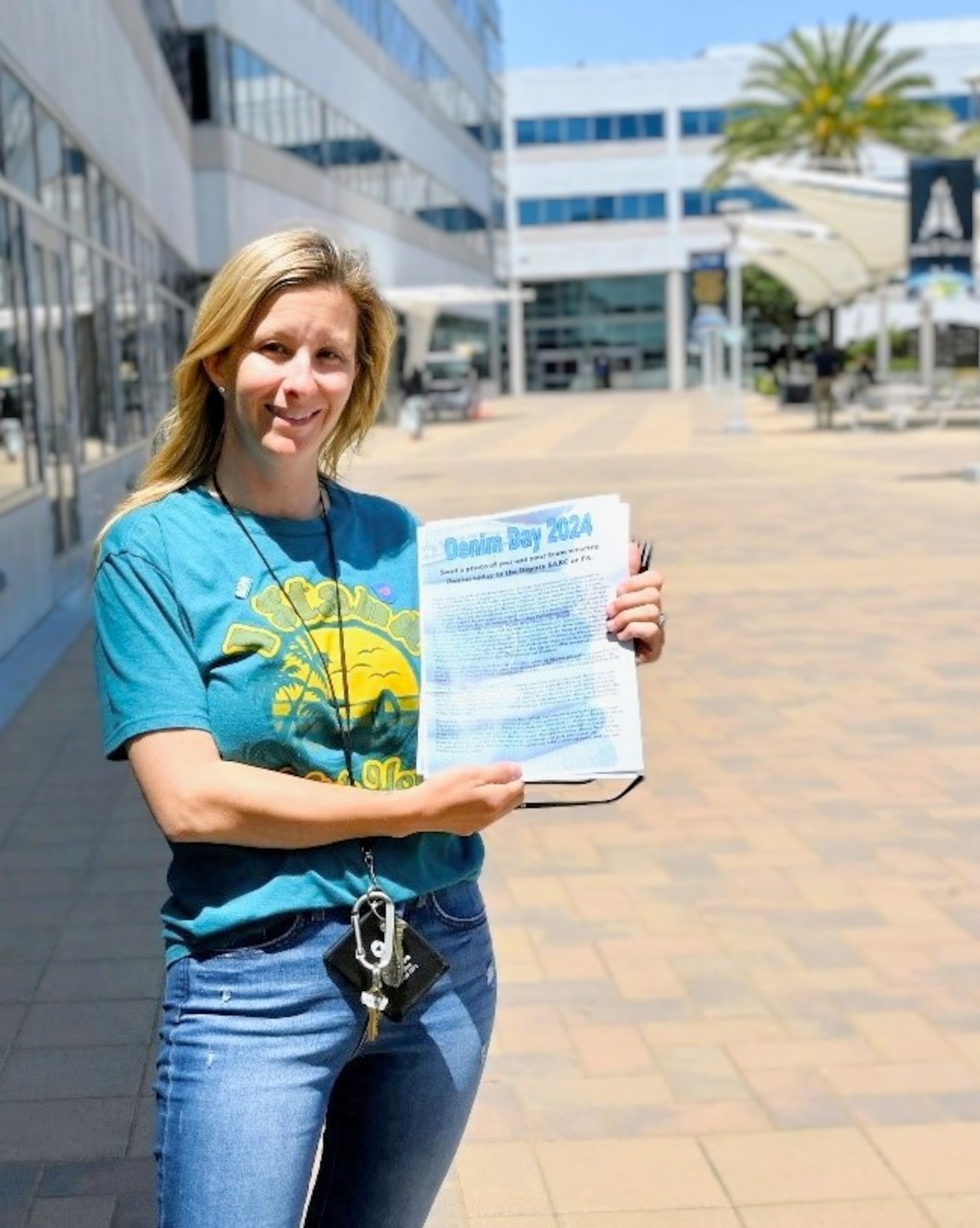 A woman wearing denim jeans holds a paper that says "Denim Day 2024).
