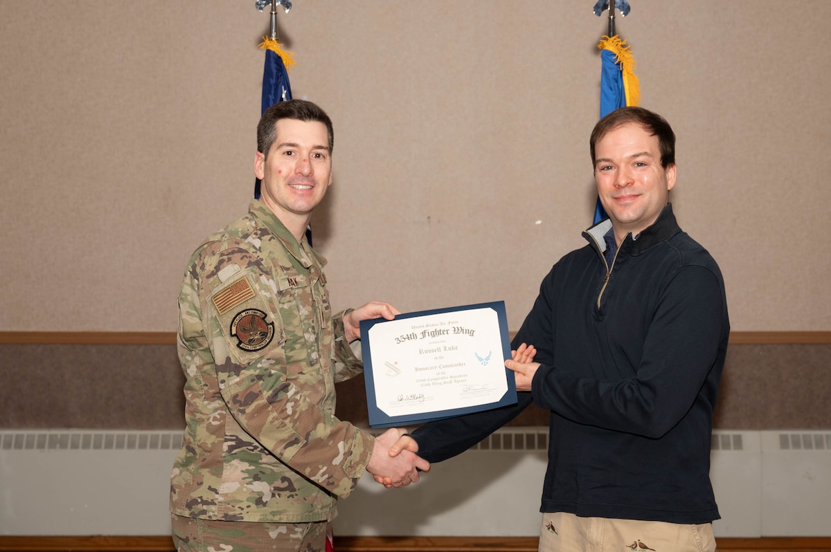 U.S. Air Force Maj. Scott Kozlak, 354th Comptroller Squadron commander, presents Russell Luke, University of Alaska Fairbanks Political Science assistant professor, with a honorary commander certificate during the Honorary Commander Induction Ceremony at Eielson Air Force Base, Alaska, Dec. 5, 2024.