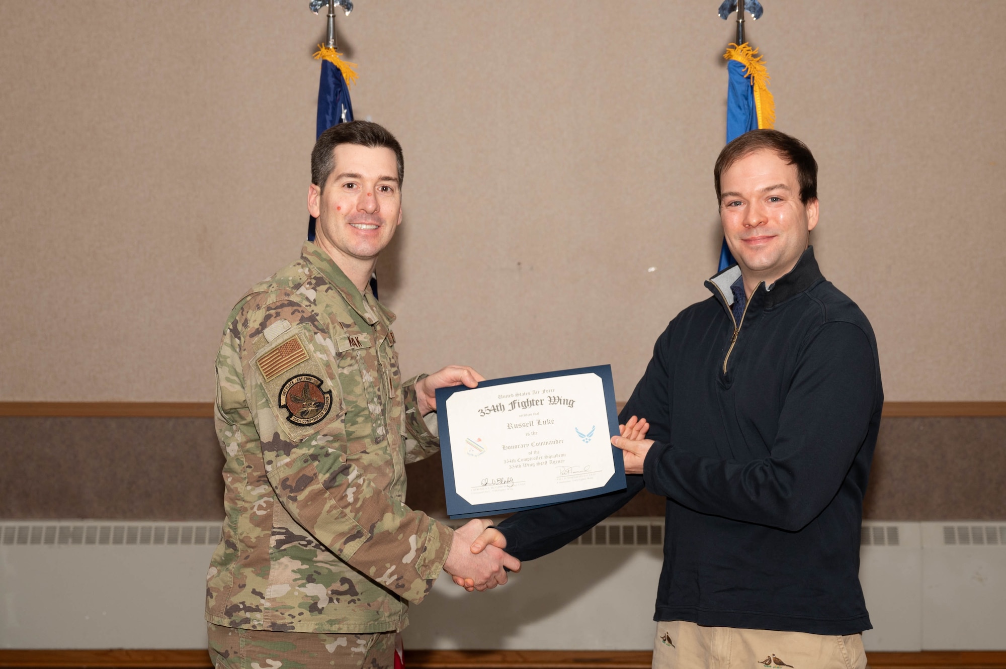 U.S. Air Force Maj. Scott Kozlak, 354th Comptroller Squadron commander, presents Russell Luke, University of Alaska Fairbanks Political Science assistant professor, with a honorary commander certificate during the Honorary Commander Induction Ceremony at Eielson Air Force Base, Alaska, Dec. 5, 2024.