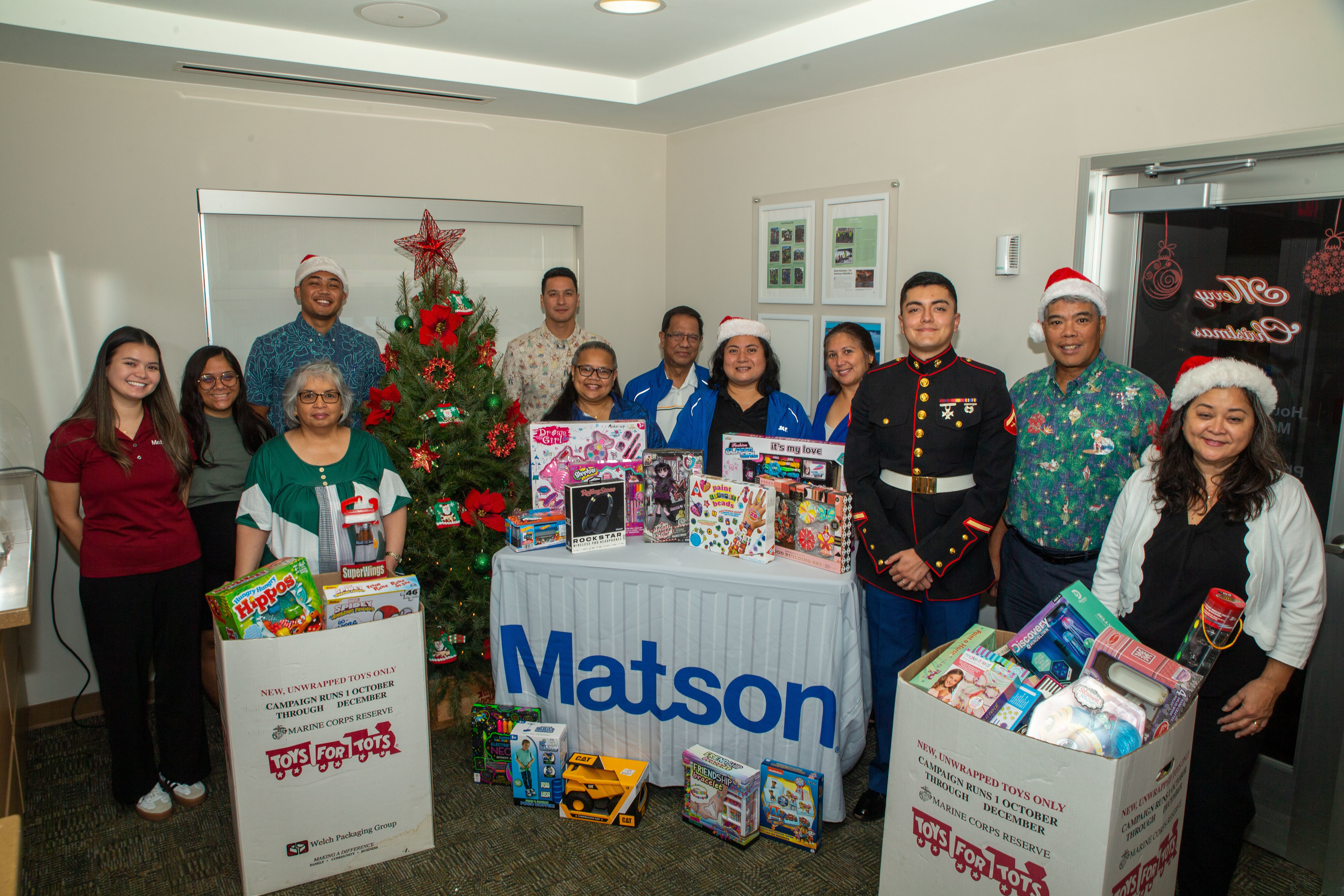 U.S. Marine Corps Lance Cpl. Cesar Gutierrez, an operations specialist, Marine Corps Base Camp Blaz, poses for a group photo with the Matson employees during the 2024 Toys for Tots toy collection, Asan-Maina, Guam, Dec. 6, 2024. The Marine Corps Toys for Tots program collects new unwrapped toys for distribution to children in the local area and neighboring Commonwealth of the Mariana Islands during the holiday season. (U.S. Marine Corps photo by Lance Cpl. Afton Smiley)