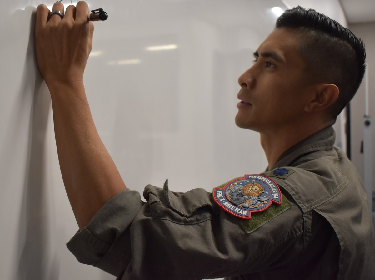 Man in uniform writing on white board