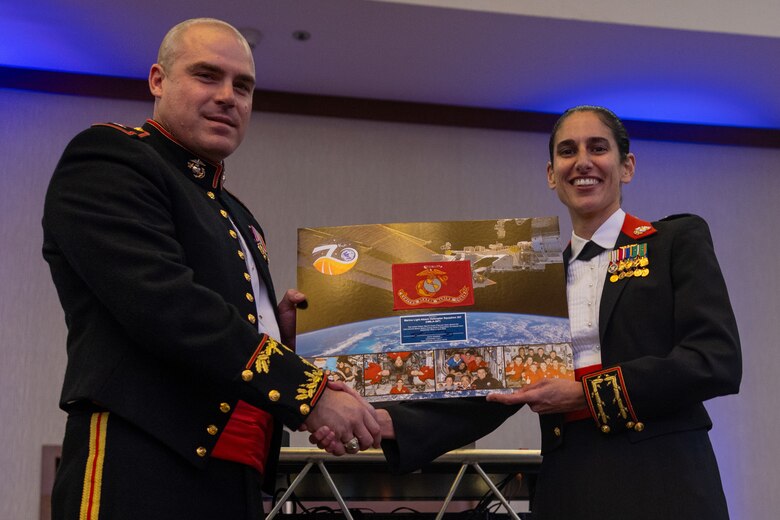 U.S. Marine Corps Lt. Col. Jasmin Moghbeli, right, a New York native and NASA astronaut, presents a Marine Corps flag that was flown on the International Space Station in honor of Marine Light Attack Helicopter Squadron (HMLA) 367, Marine Aircraft Group 39, 3rd Marine Aircraft Wing to Lt. Col. Greg Watten, a California native and commanding officer of HMLA-367, during the HMLA-367 Marine Corps Birthday Ball in La Jolla, California, Dec. 13, 2024.