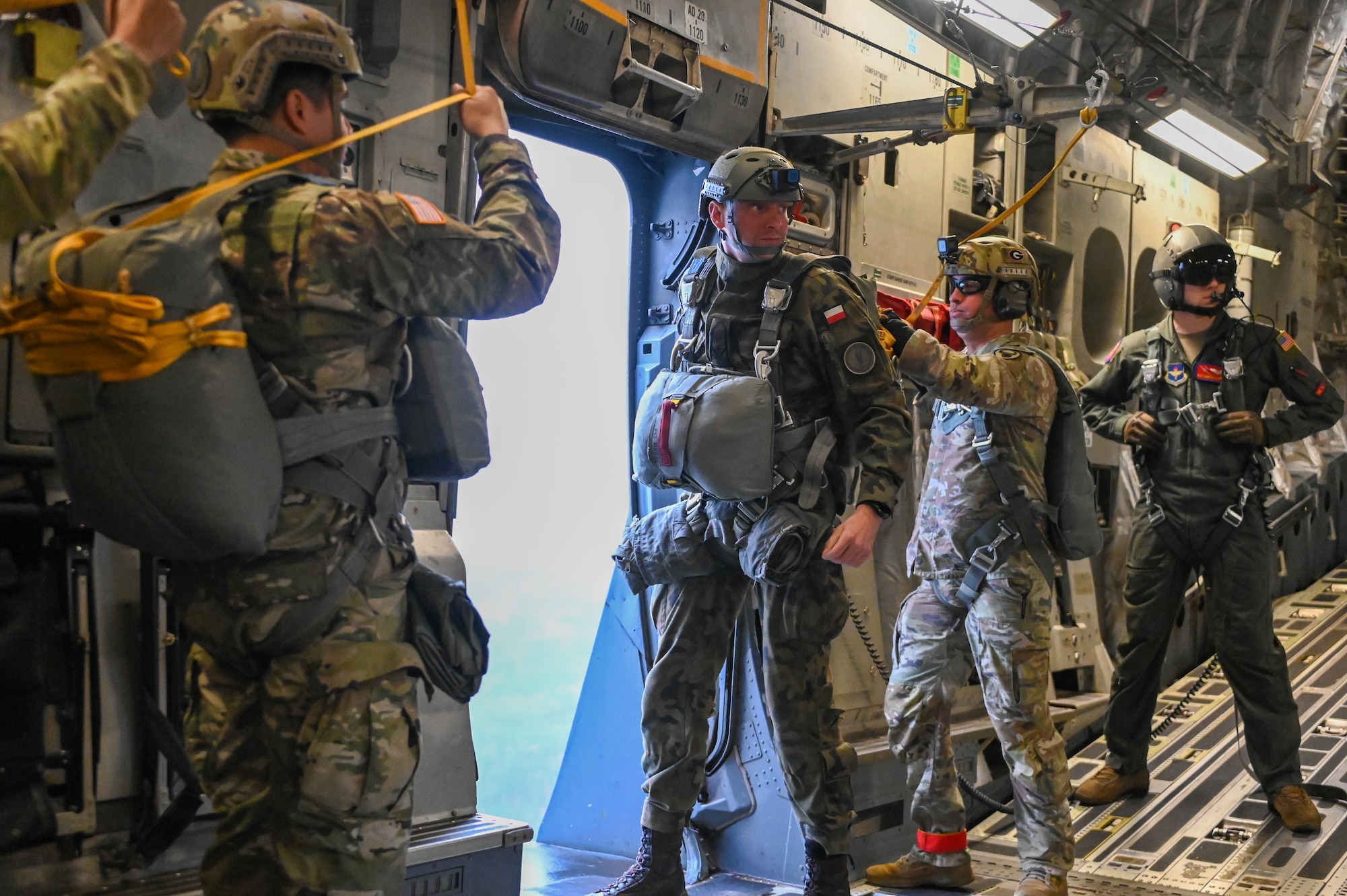 A jumpmaster from the Polish Armed Forces looks for a signal during an air drop over Drop Zone Sicily at Fort Liberty, North Carolina, Dec. 9, 2024. Many of the U.S. Soldiers received jumpwings from the foreign ally jumpmasters after the drops. (U.S. Air Force photo by Senior Airman Kari Degraffenreed)