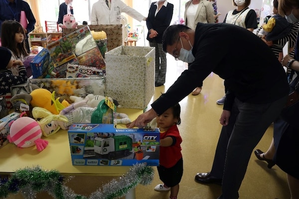 241217-N-DO281-1003 OKINAWA, Japan (Dec. 17, 2024) – Lt. Cmdr. Dinh Ngo shows a toy to a child during a toy dive at Nambu Medical Center & Nambu Children’s Medical Center in Okinawa, Japan, Dec. 17, 2024. (U.S. Navy photo by Mass Communication Specialist 1st Class Trey Fowler)