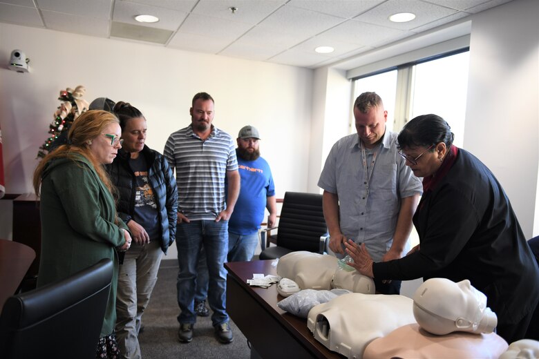 Woman performs chest compressions on a mannequin while student observe