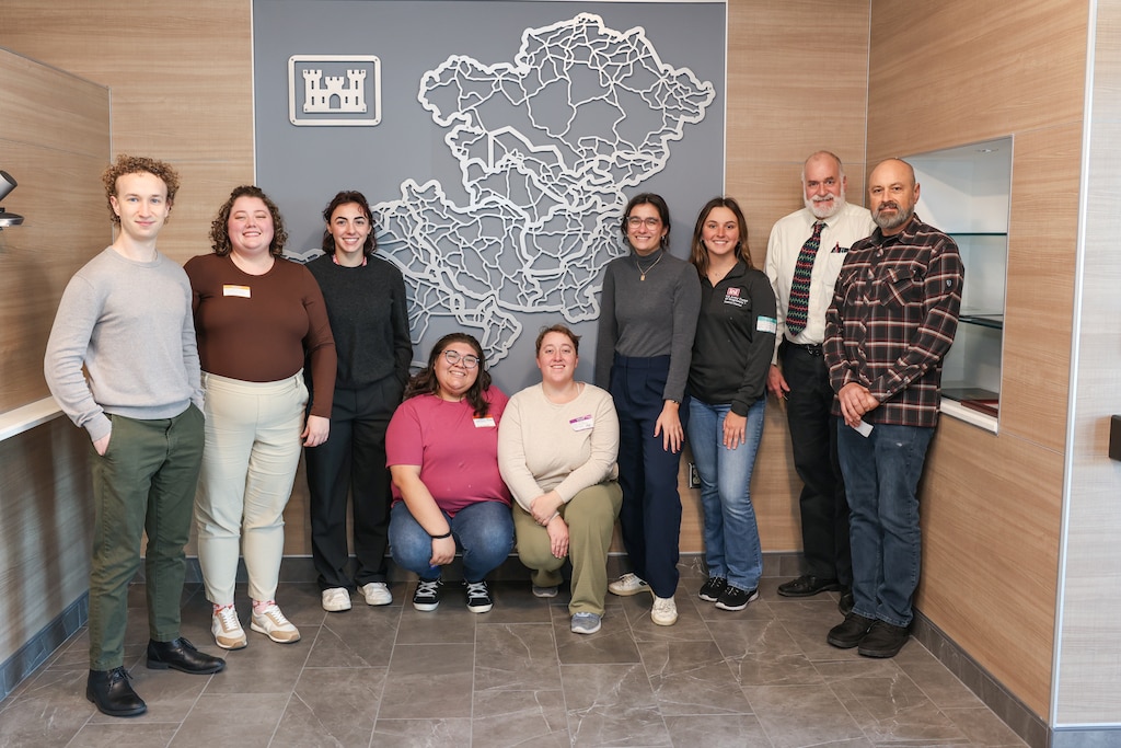 Group of people pose in front of a map of the Middle East.