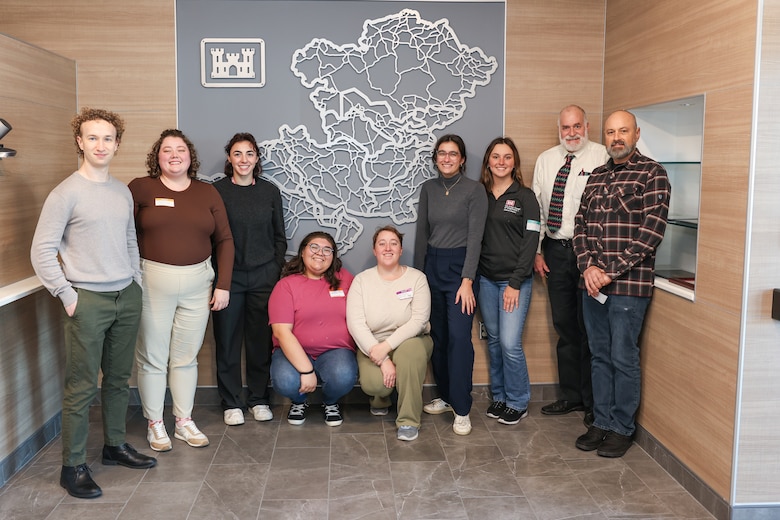 Group of people pose in front of a map of the Middle East.
