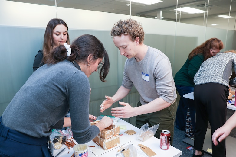 People building structures with graham cracker cookies and icing.