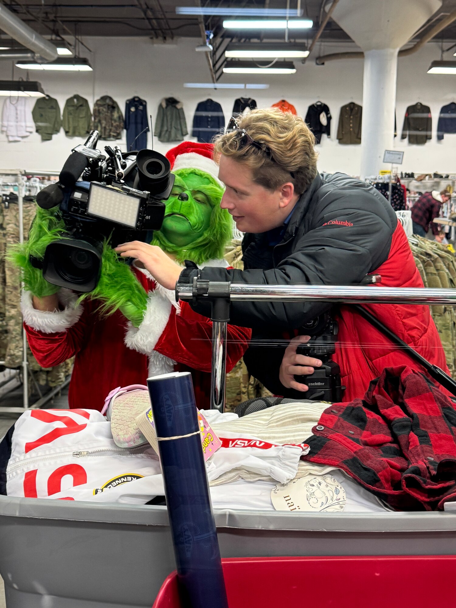 The Grinch and a man looking at a video camera together figuring out how it works.