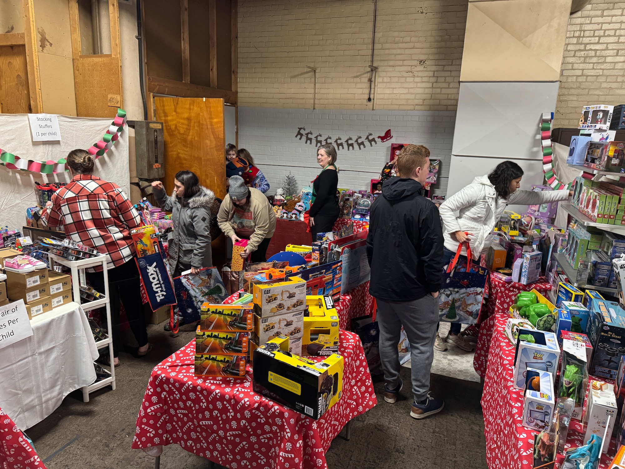 Families walk around a room filled with toys selecting them for there children.