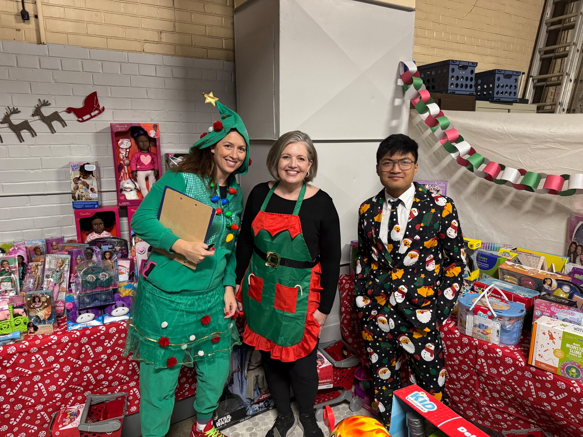 three people stand in front of toys for a photo