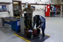 U.S. Air Force Tech. Sgt. Michael Otter, 9th Maintenance Squadron (MXS) egress systems craftsman, and Charlie Toomer, 9th MXS egress systems craftsman, prepare a pilots seat for an inspection at Beale Air Force Base, Dec. 2, 2024.