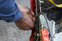 Charlie Toomer, 9th Maintenance Squadron egress systems craftsman, demonstrates use of a pin necessary to allow the egress systems on a pilots seat to function at Beale Air Force Base, Dec. 2, 2024.