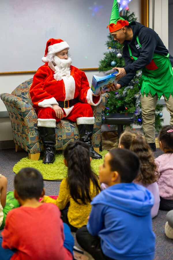 U.S. Marine Corps Gunnery Sgt. Niko Azucenas, hands a toy to Capt. Michael McDonald, dressed as Santa Claus, to give to a student at June Nelson Elementary School during a Toys for Tots event in Kotzebue, Alaska, Dec. 5, 2024. McDonald and Azucenas, inspector-instructor and company training chief, respectively, with Detachment Delta Company, 4th Law Enforcement Battalion, Force Headquarters Group, along with members of the Air Force and Navy, passed out toys to local school children during this year’s Toys for Tots operation. The Toys for Tots mission exemplifies the Marine Corps spirit in the Last Frontier, strengthening community ties while sharpening the Marines' readiness for Arctic operations.  (U.S. Marine Corps photo by Sgt. Ethan M. LeBlanc)