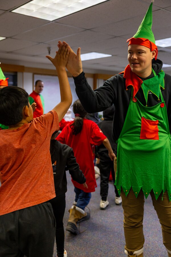 U.S. Navy Petty Officer 2nd Class Curtis Darrow, right, high-fives a student member of June Nelson Elementary School as they arrive to "Santa’s Workshop” while handing out toys in Kotzebue, Alaska, Dec. 5, 2024. Darrow, a hospital corpsman with Detachment Delta Company, 4th Law Enforcement Battalion, Force Headquarters Group, Marine Forces Reserve, along with members of the Air Force and Navy, passed out toys to local school children during this year’s Toys for Tots operation. The Toys for Tots mission exemplifies the Marine Corps spirit in the Last Frontier, strengthening community ties while sharpening the Marines' readiness for Arctic operations.  (U.S. Marine Corps photo by Sgt. Ethan M. LeBlanc)
