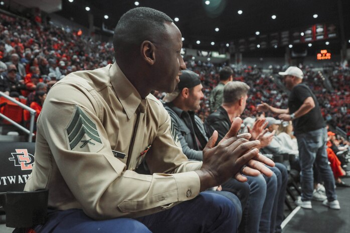 U.S. Marine Corps Sgt. Dennis Maina, assistant for Officer Selection Team San Diego, Recruiting Station San Diego, watches the San Diego State University Men's Basketball game in San Diego, California, Dec. 11, 2024. Maina was recognized as the guest of honor during the game. The guest of honor received special recognition including a formal introduction, reserved seating and participation in game-day activities. (U.S. Marine Corps photo by Cpl. Alejandro Fernandez)
