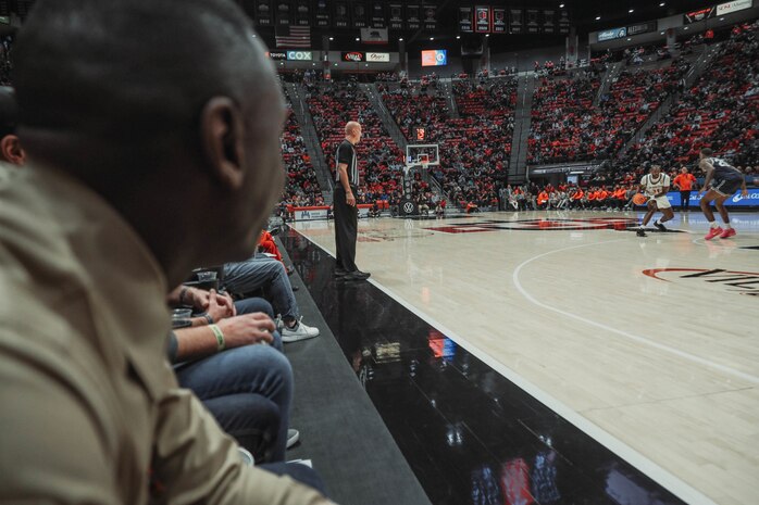 U.S. Marine Corps Sgt. Dennis Maina, assistant for Officer Selection Team San Diego, Recruiting Station San Diego, watches the San Diego State University Men's Basketball game in San Diego, California, Dec. 11, 2024. Maina was recognized as the guest of honor during the game. The guest of honor received special recognition including a formal introduction, reserved seating and participation in game-day activities. (U.S. Marine Corps photo by Cpl. Alejandro Fernandez)