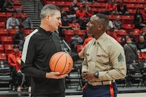 U.S. Marine Corps Sgt. Dennis Maina, assistant for Officer Selection Team San Diego, Recruiting Station San Diego,  talks to a referee during the San Diego State University Men's Basketball game in San Diego, California, Dec. 11, 2024. Maina was recognized as the guest of honor during the game. The guest of honor received special recognition including a formal introduction, reserved seating and participation in game-day activities. (U.S. Marine Corps photo by Cpl. Alejandro Fernandez)