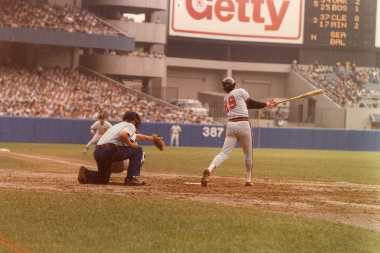 A baseball player swings at a baseball.