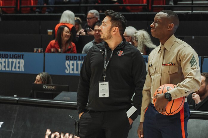 U.S. Marine Corps Sgt. Dennis Maina, assistant for Officer Selection Team San Diego, Recruiting Station San Diego,  awaits the guest of honor presentation during the San Diego State University Men's Basketball game in San Diego, California, Dec. 11, 2024. Maina was recognized as the guest of honor during the game. The guest of honor received special recognition including a formal introduction, reserved seating and participation in game-day activities. (U.S. Marine Corps photo by Cpl. Alejandro Fernandez)