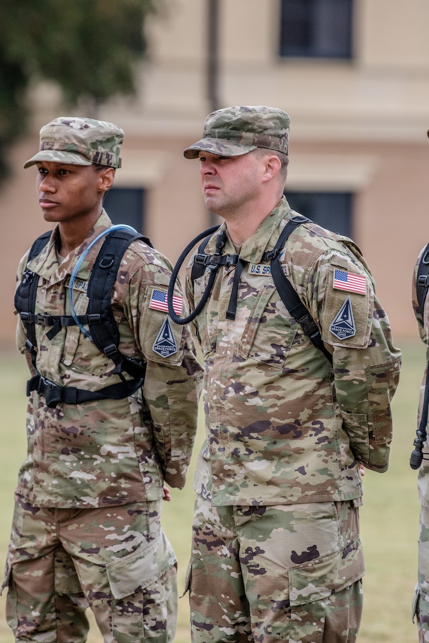 Two airmen stand at attention outside.