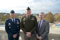 An Airman, Soldier and civilian stand together with a view of the U.S. Monument in the background