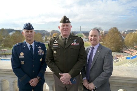 An Airman, Soldier and civilian stand together with a view of the U.S. Monument in the background