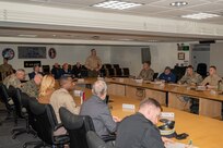 Service members and civilians gather around a conference table talking