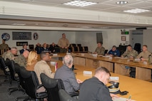 Service members and civilians gather around a conference table talking