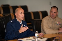 Service members and civilians gather around a conference table talking