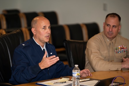 Service members and civilians gather around a conference table talking