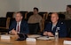 Service members and civilians gather around a conference table talking