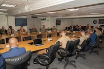 Service members and civilians gather around a conference table talking