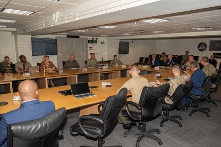Service members and civilians gather around a conference table talking