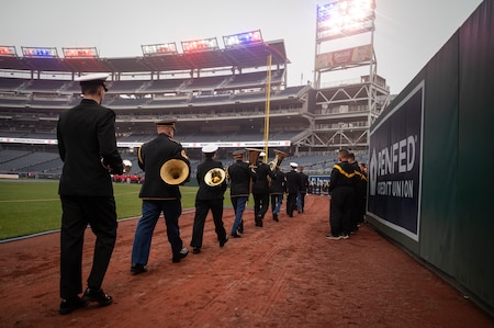 service members walking with instruments on a field