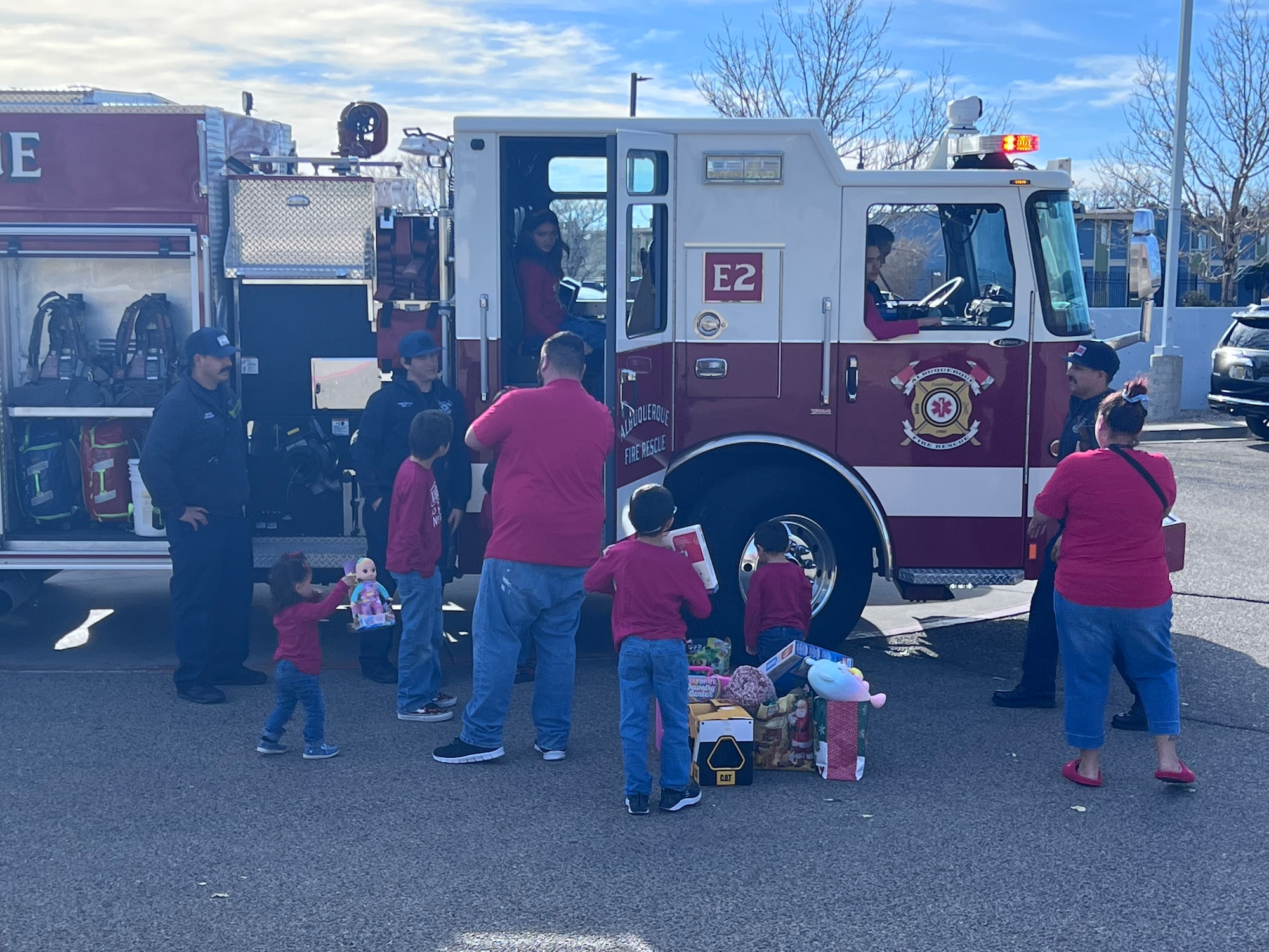 Families stand in front of a fire truck waiting for gifts from santa