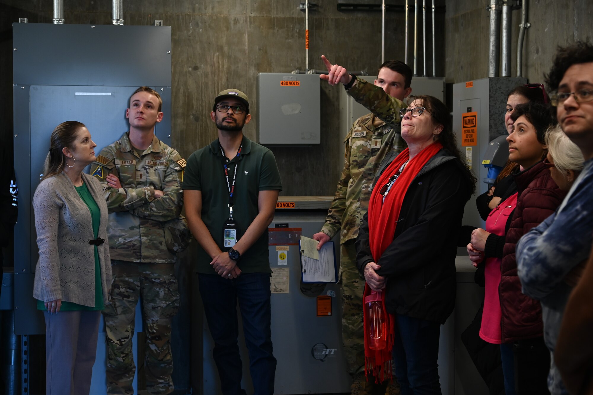 people walking around different areas of a launch facility, metal tower involved, rooms with wires and buttons as well.