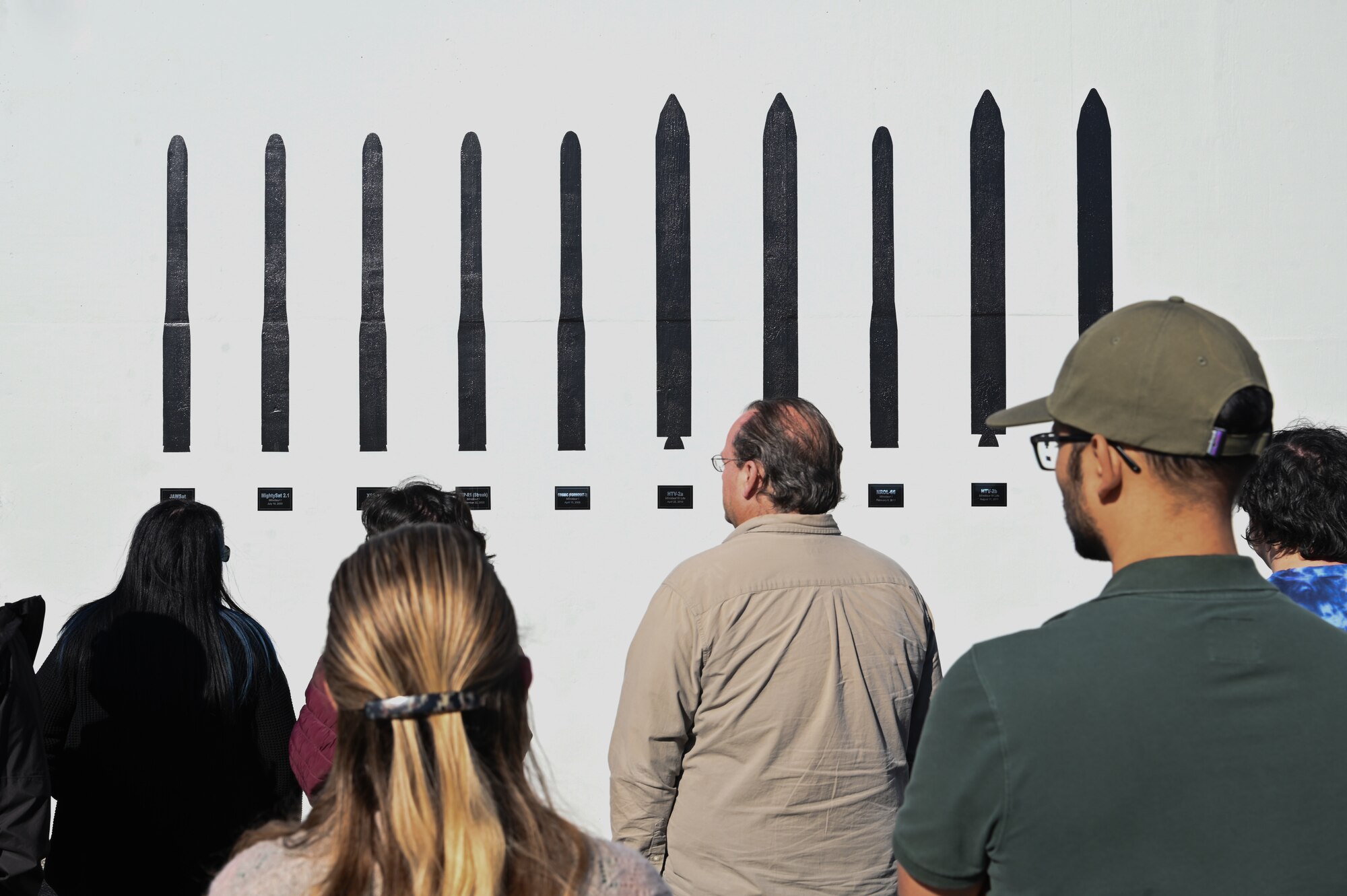 people walking around different areas of a launch facility, metal tower involved, rooms with wires and buttons as well.