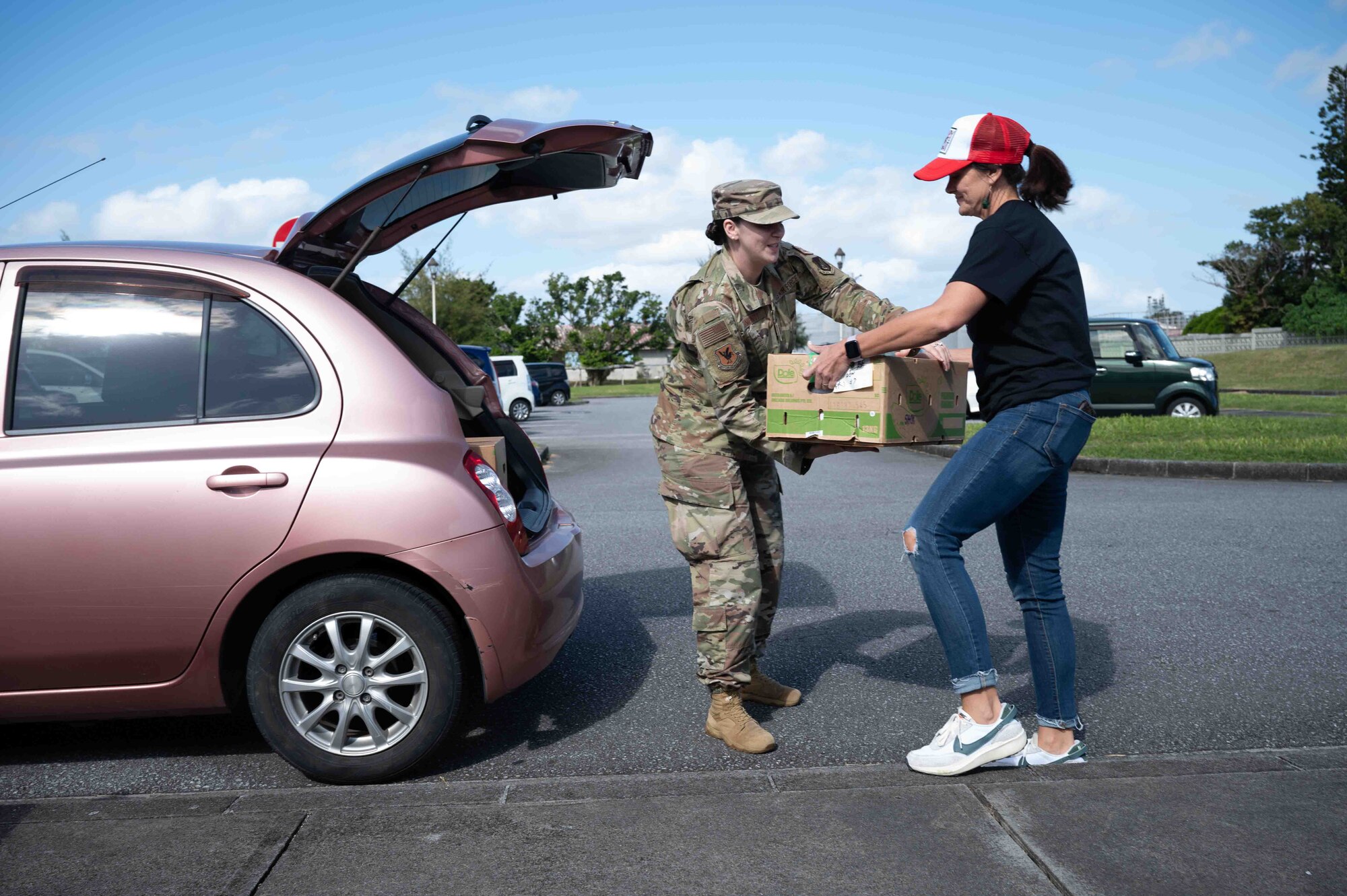 volunteer hand a box to a service member to pack into their car