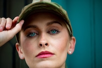 woman in uniform stares directly into camera with bright blue eyes and pink lipstick