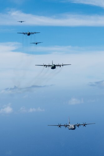 A formation of C-130J Super Hercules and C-130H Hercules aircraft fly together over the Pacific Ocean, Dec. 14, 2024, to culminate Operation Christmas Drop 2024.