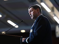 A military member speaks at a podium.