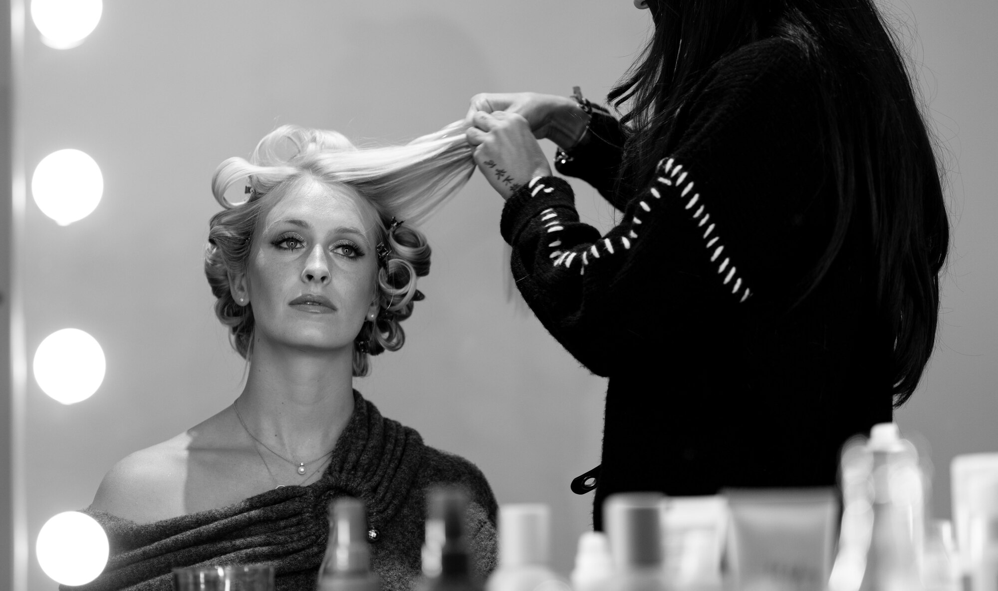 women reflected in vanity mirror getting her hair curled