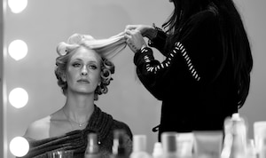 women reflected in vanity mirror getting her hair curled