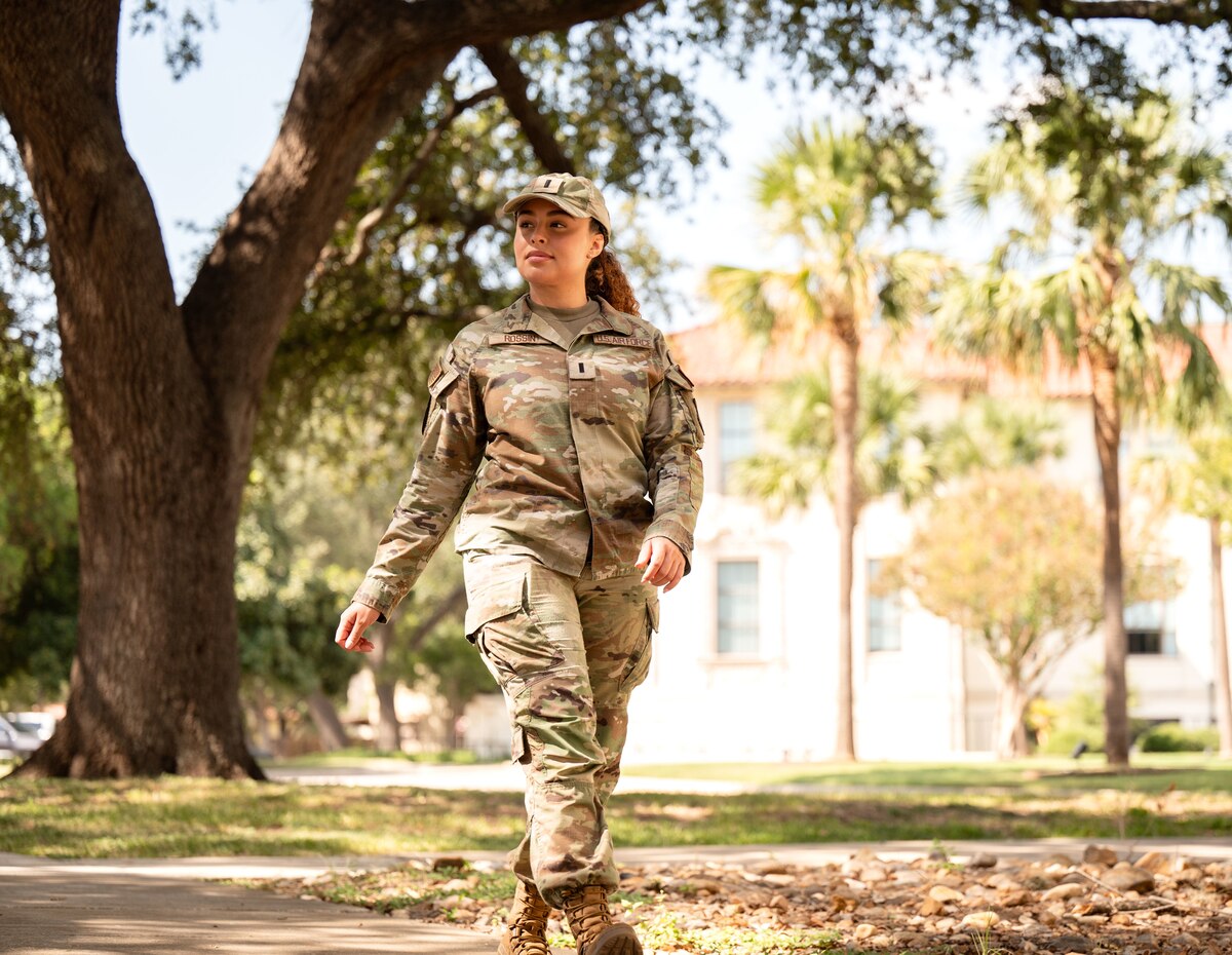 woman in uniform walks down a sidewalk