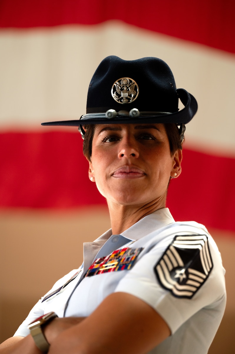 woman in uniform crosses arms and poses in front of American flag