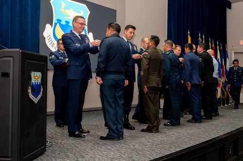 Col. Bryan Tuinman, commandant of the Inter-American Air Forces Academy and Chief Maurice Muro, Senior Enlisted Leader of the Inter-American Air Forces Academy pin international military students during IAAFA’s graduation