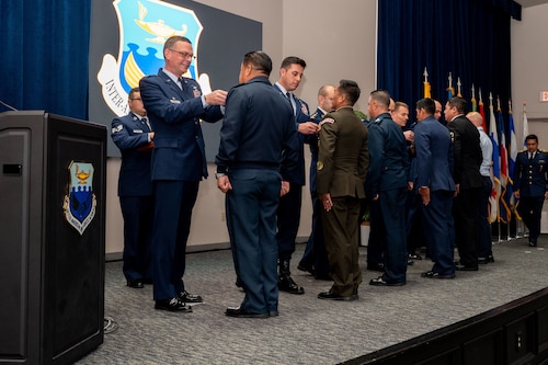 Col. Bryan Tuinman, commandant of the Inter-American Air Forces Academy and Chief Maurice Muro, Senior Enlisted Leader of the Inter-American Air Forces Academy pin international military students during IAAFA’s graduation